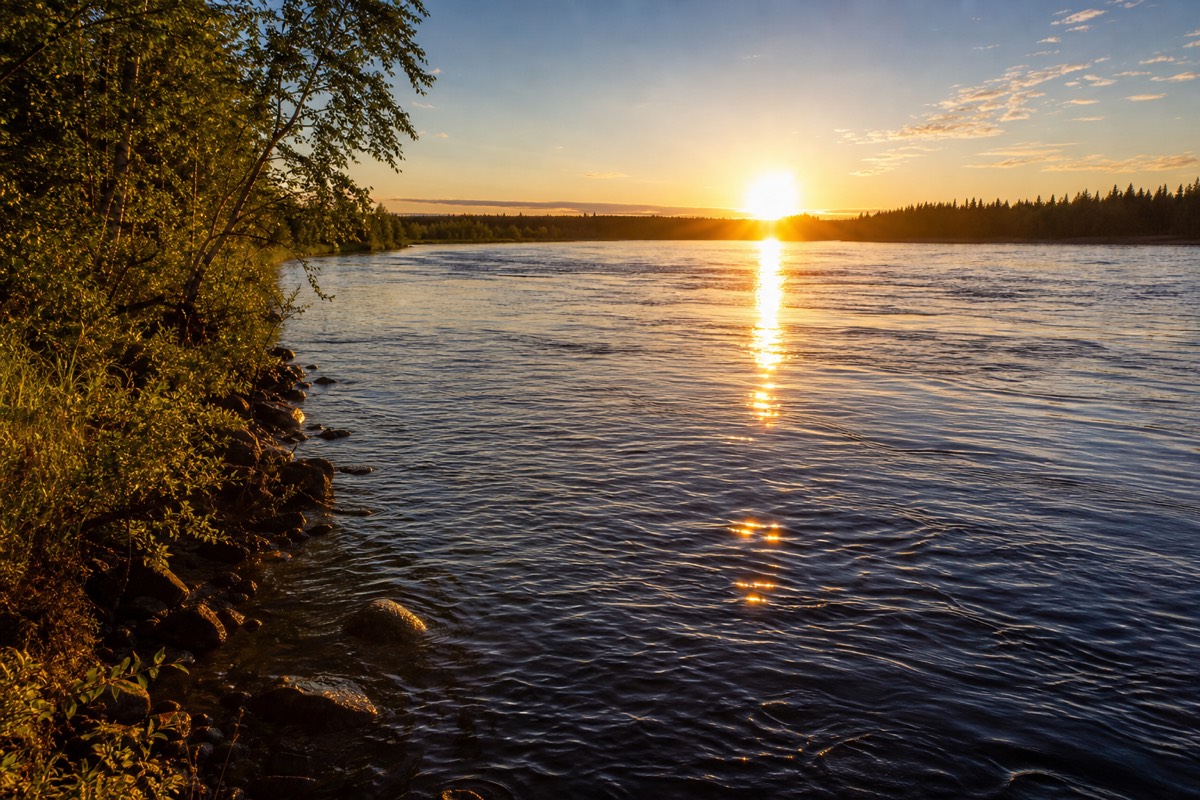 The midnight sun low over the Ounasjoki river in summer